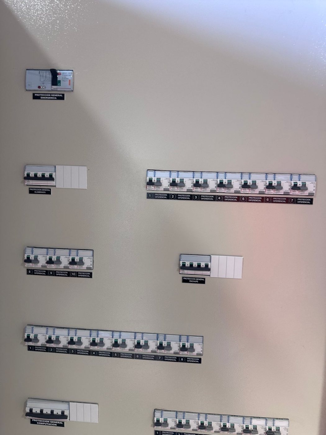Cubierta frontal de tablero eléctrico con cada circuito rotulado: protección general, alumbrado, enchufes y computación